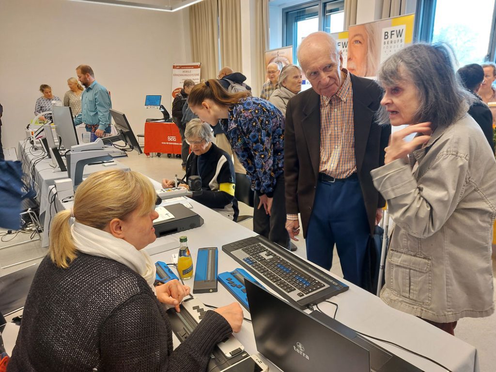 Besucher stehen bei den Ausstellerständen, probieren verschiedene Hilfsmittel aus und lassen sich beraten.