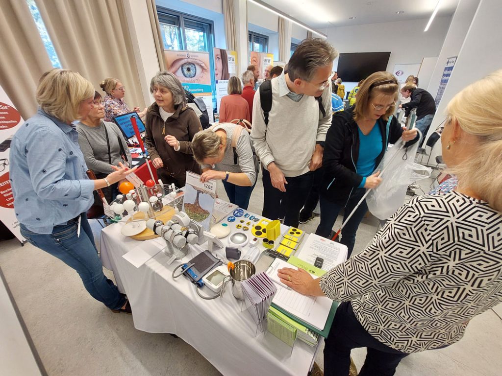 Am Stand des Landeshilfsmittelzentrums finden Gespräche zwischen den Hilfsmittelberatern und den Besuchern statt.